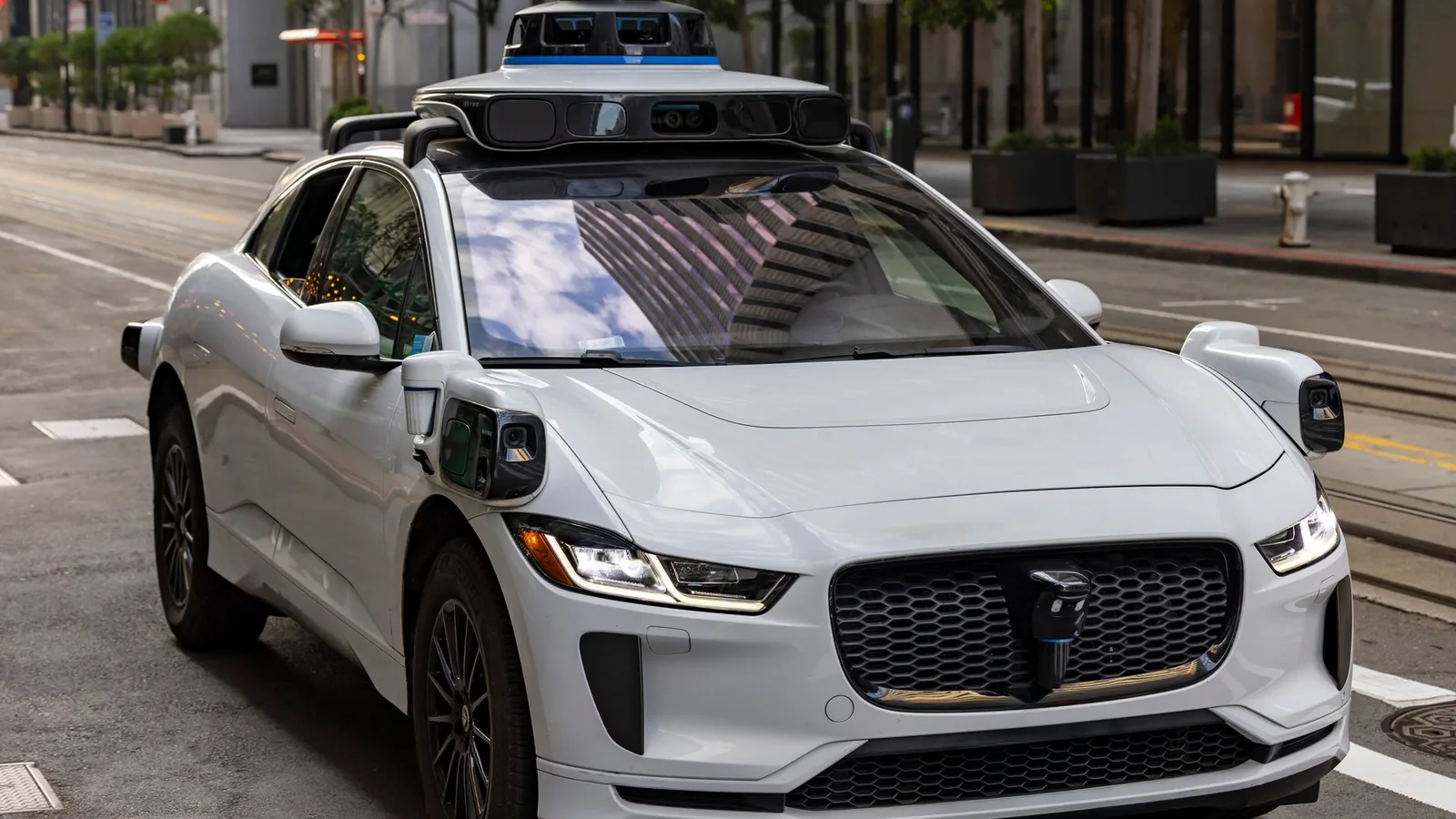A self-driving car with a roof-mounted sensor array on a city street