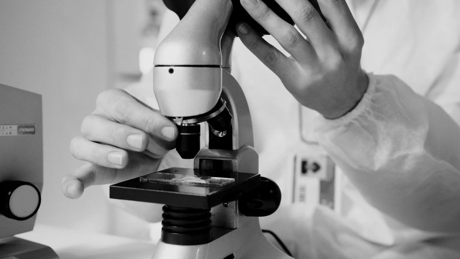 A researcher examining a sample under a microscope in a lab setting